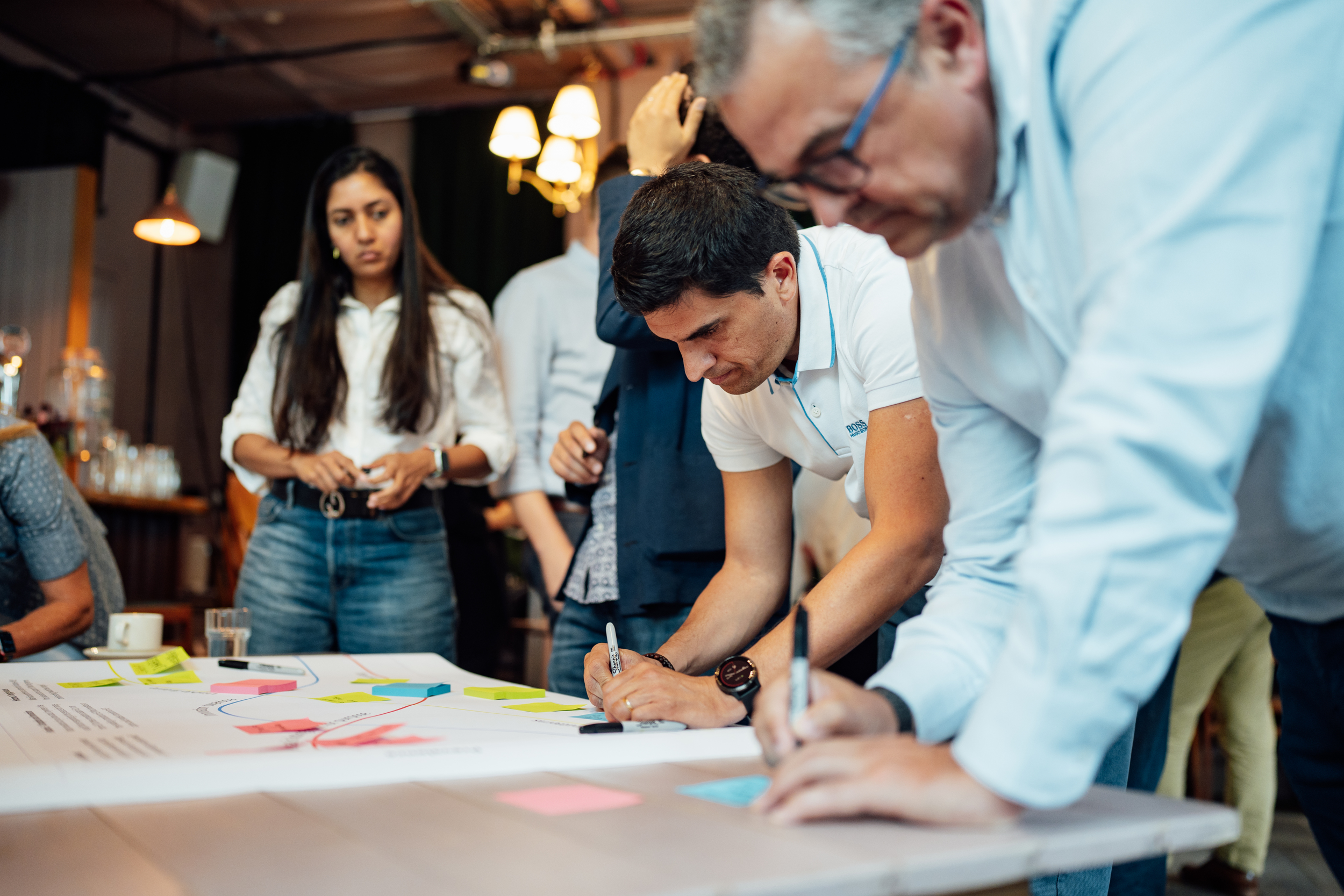 Group of people writing with pens on paper on a table