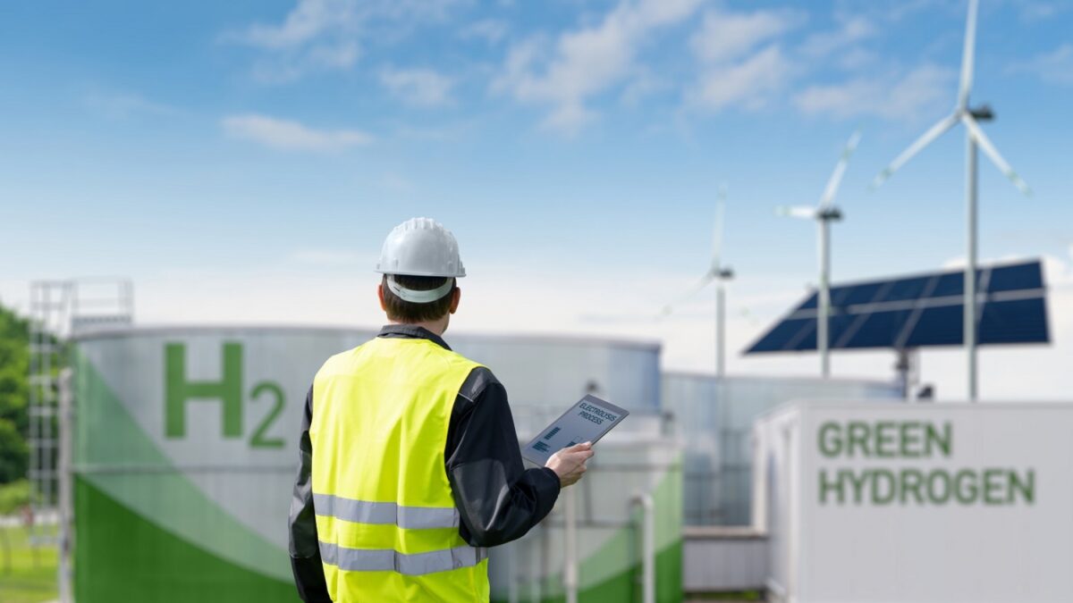 Man in high visability jacket looking at wind turbines